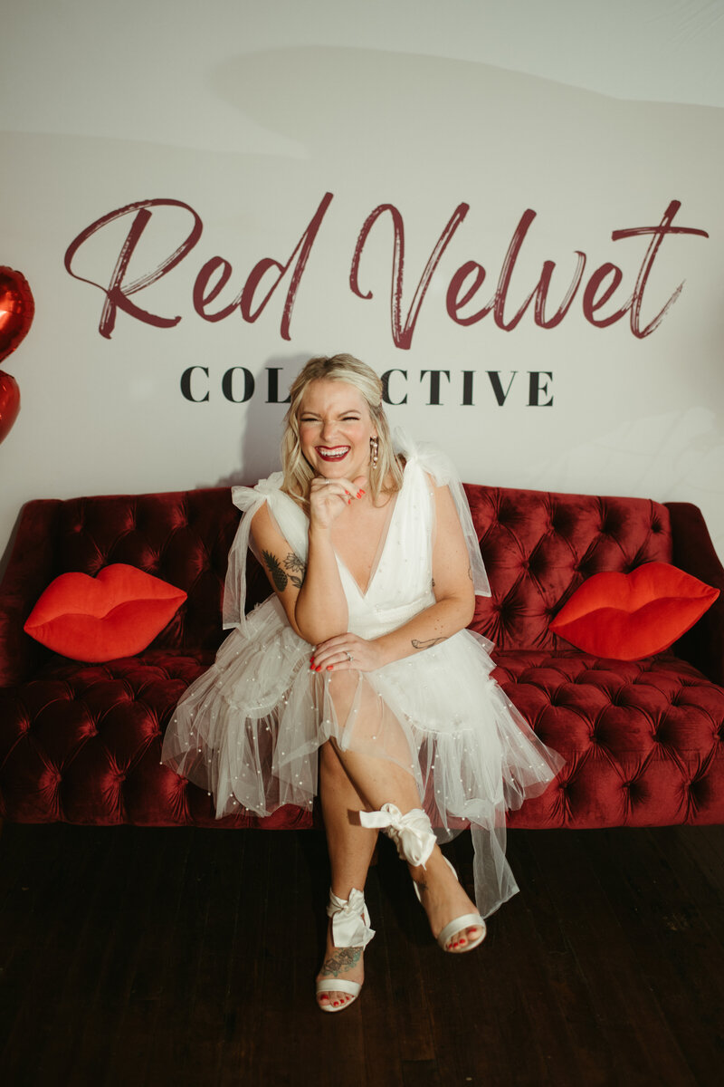 Bride sitting on red velvet couch at wedding