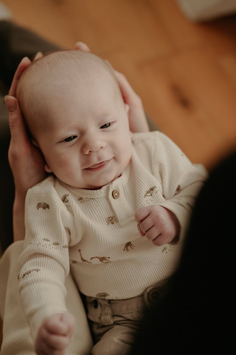 Bebis ligger i knä på sin mamma och ler.