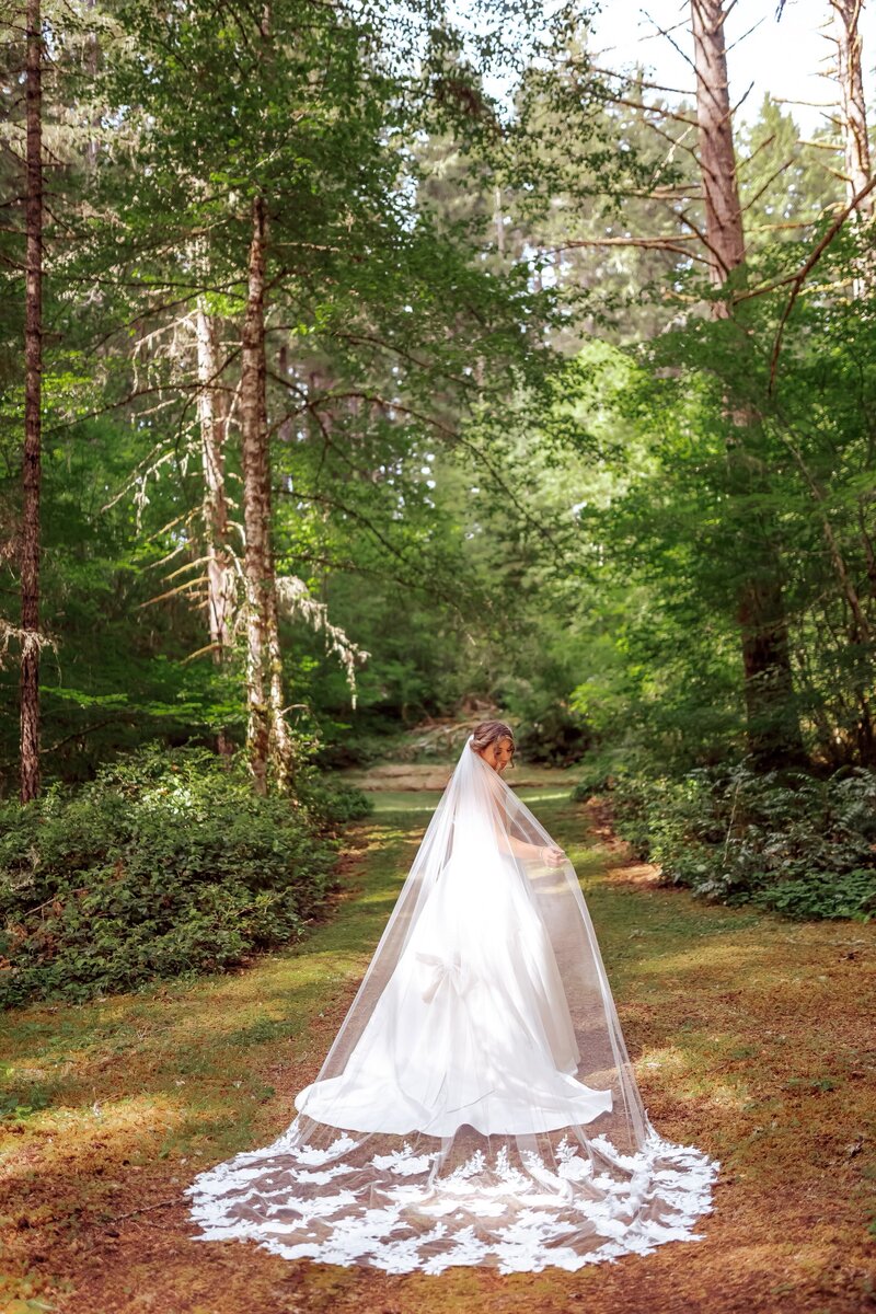 real bride Madelynn wearing her custom lace veil with heirloom items while posing in the forest