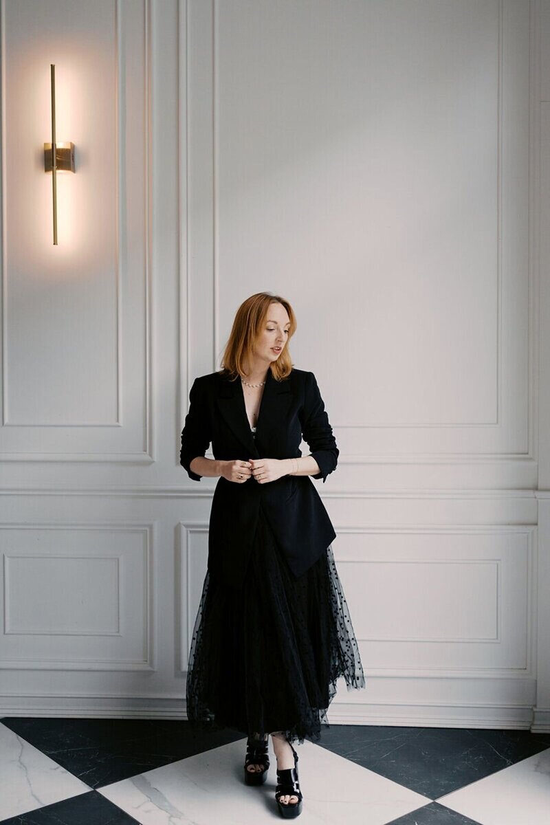 Raleigh photographer Rae Marshall in black attire, captured against the sleek, modern white backdrop