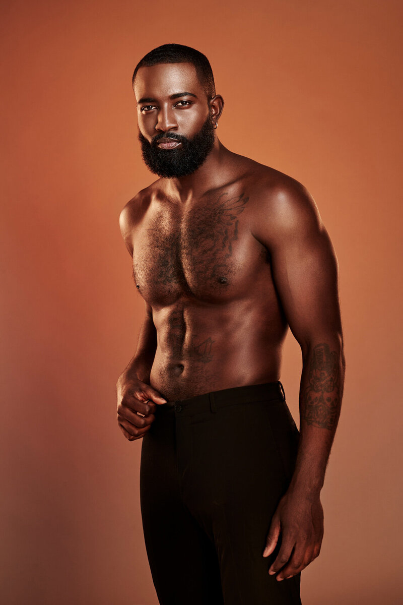 Artistic portrait of Dillard in a bold pose with a warm backdrop, captured by Ylva Erevall.