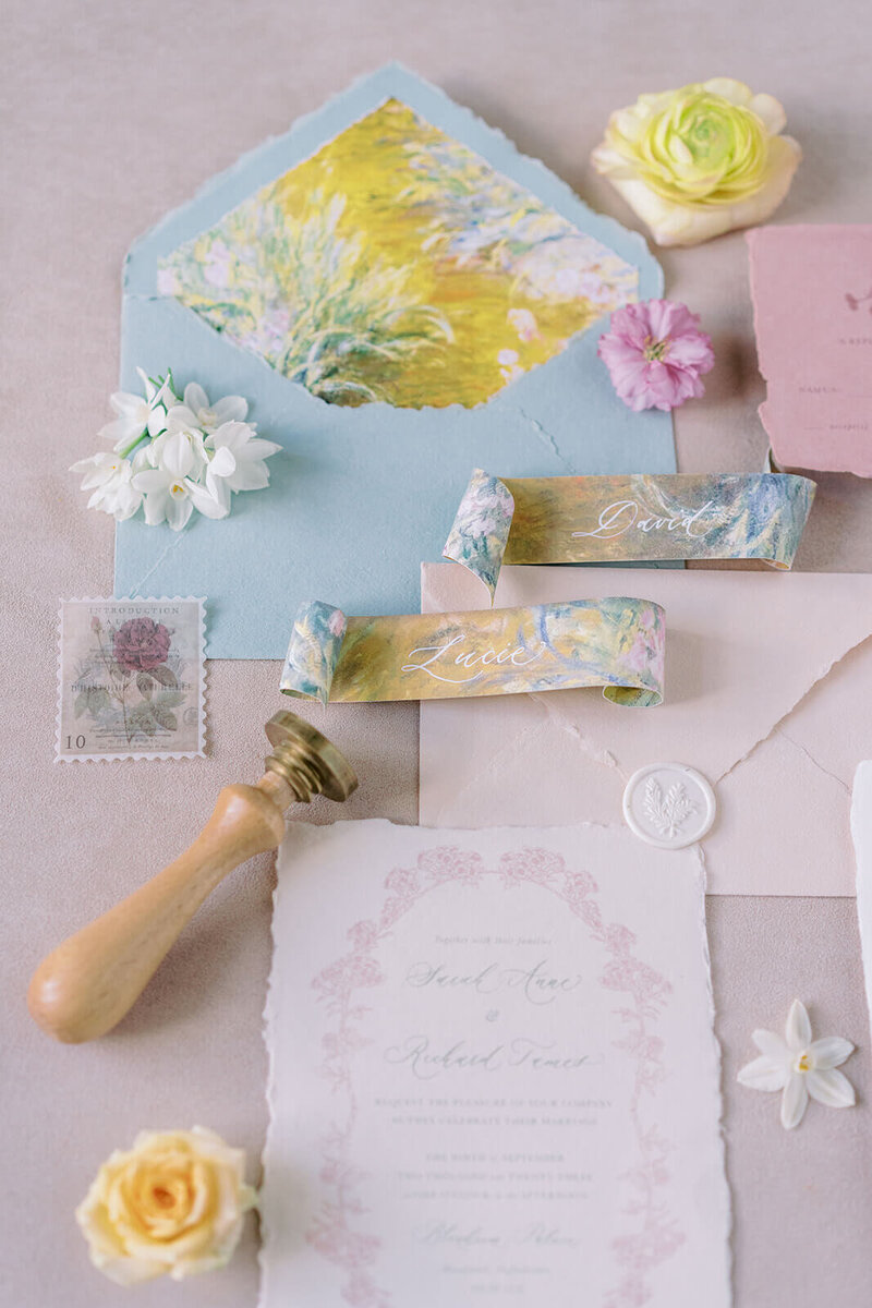 flatlay of a pink and blue luxury wedding stationery suite featuring floral scrolled place cards designed for westacott weddings and events