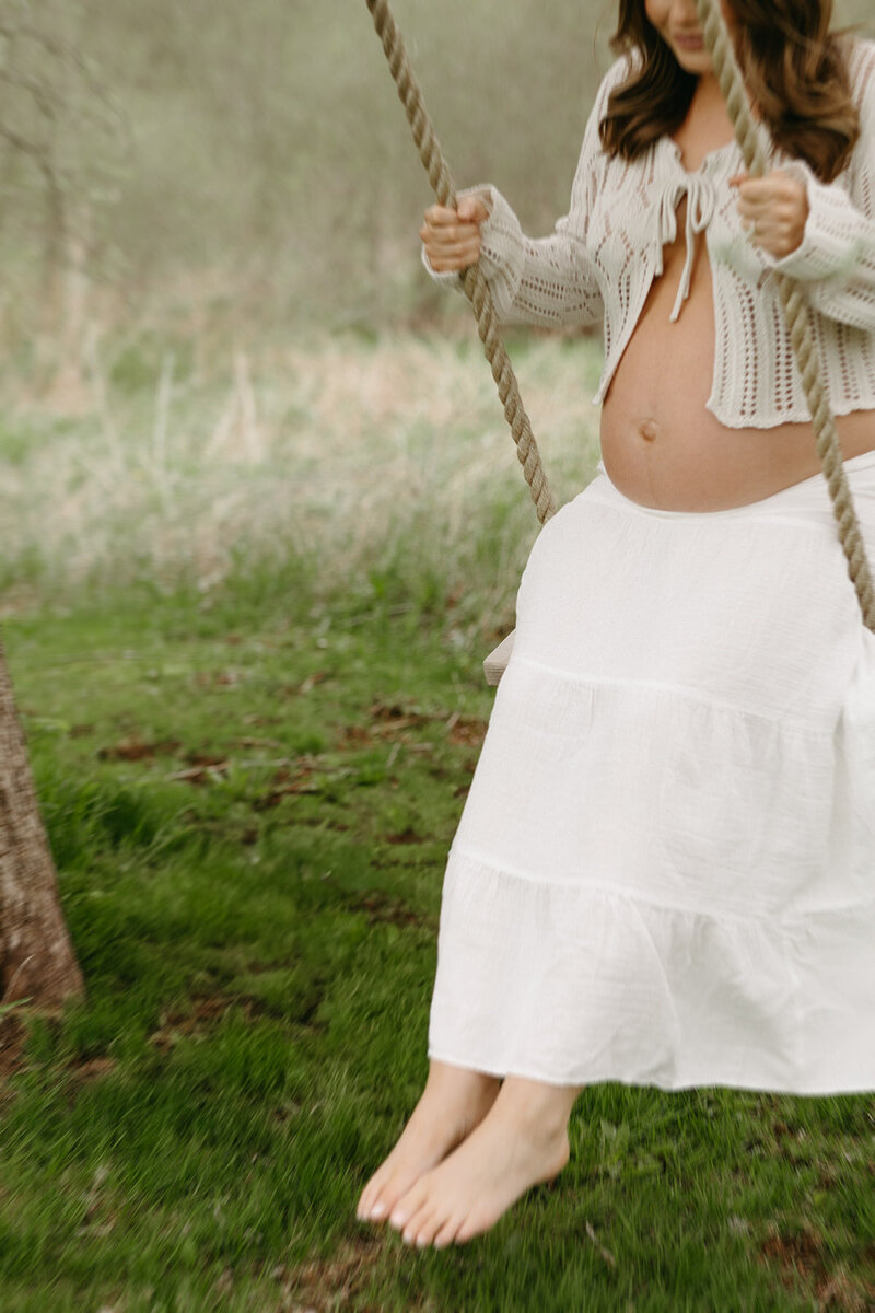 woman holds baby bump during lifestyle session in pei