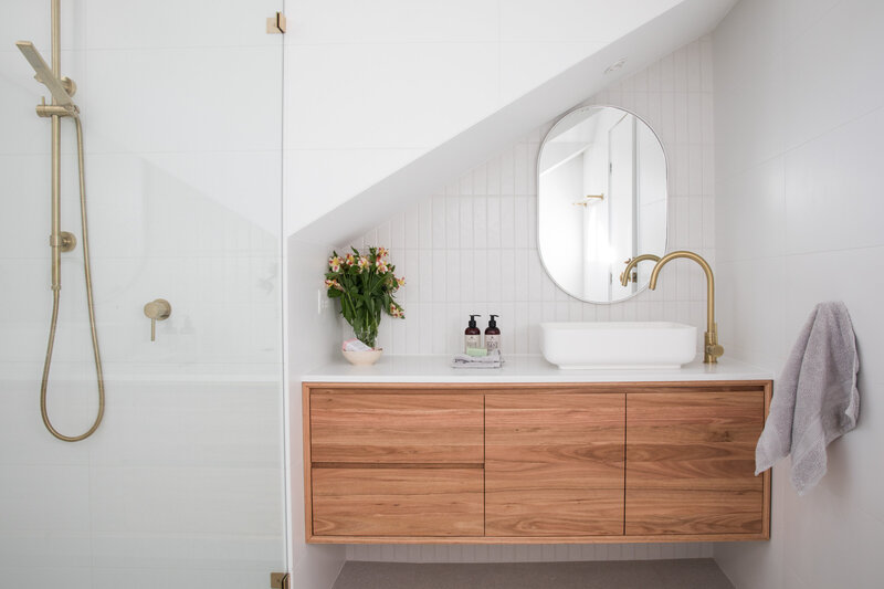 modern and calming bathroom design with glass shower doors and gold accents. 