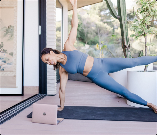 Women holding a side plank while looking at a laptop screen
