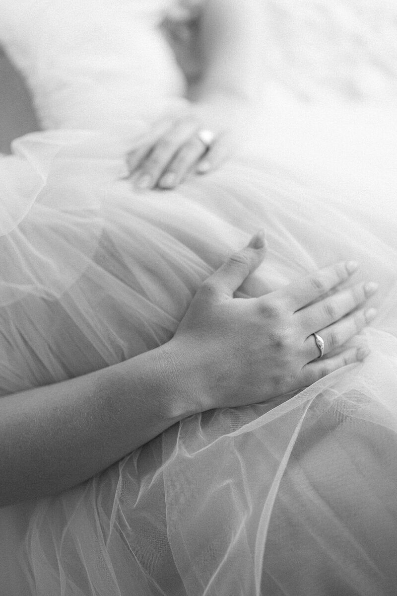 black and white image of a mother's hands holding her pregnant belly in a tulle dress during a session with Indianapolis maternity photographer Brittney Lear
