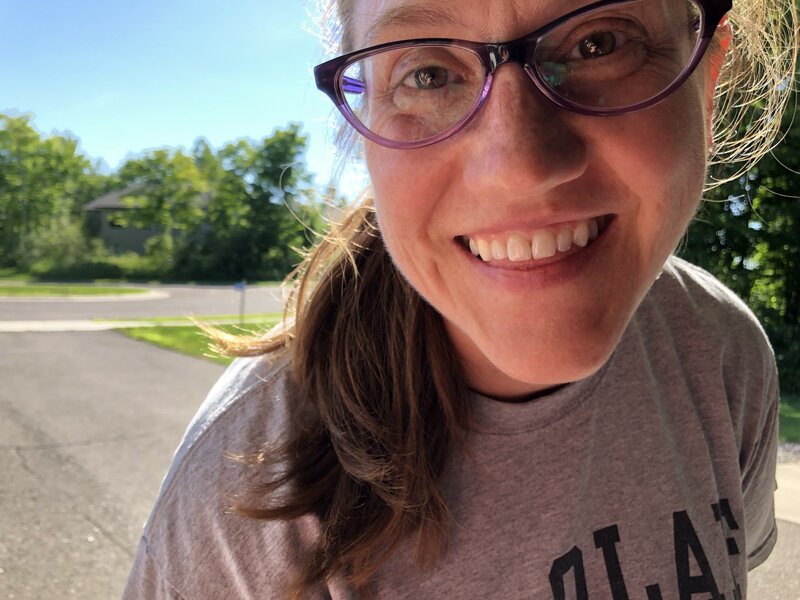 woman with glasses smiling outside