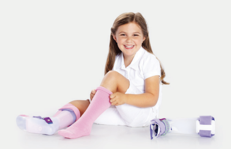 A young girl smiling while wearing an Ankle Foot Orthosis (AFO) device.