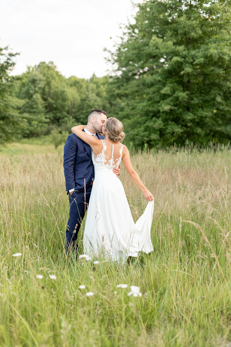 Bride and groom kissing in field