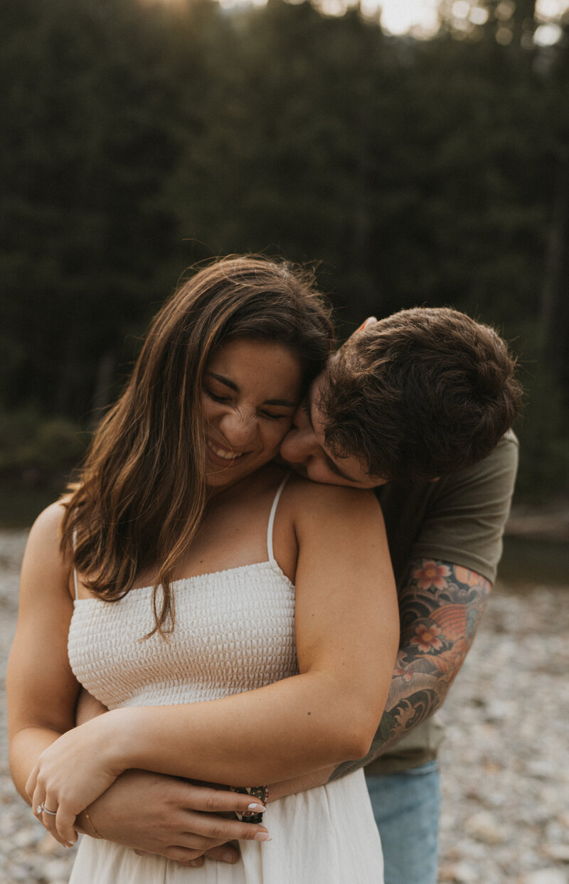 Couple laughing and hugging in Glacier National Park during photoshoot