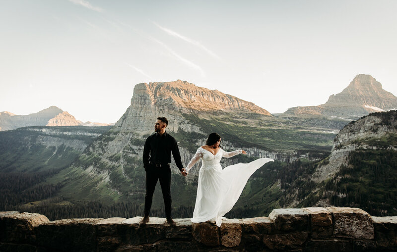 couple holding hands standing on cliff