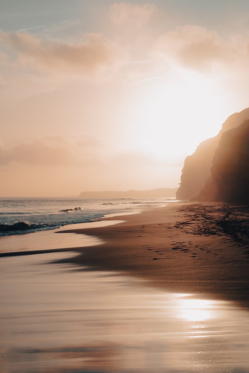 Plage entourée de falaises, au coucher du soleil