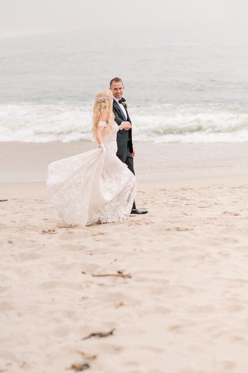 Bride and groom walk on beach