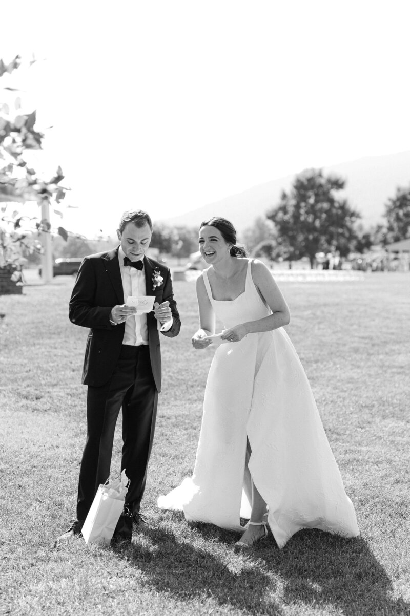 B&W photo of couple reading vows to one another while bride is laughing. Couple are in an italian vineyard.