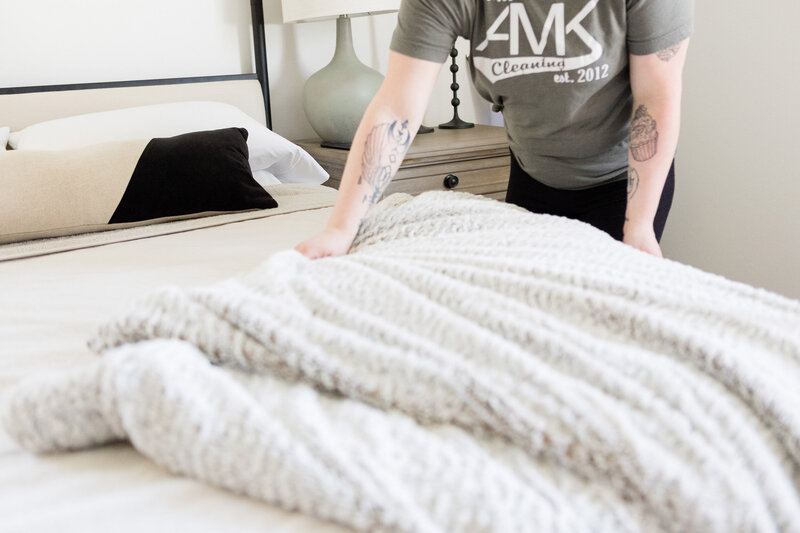 Professional cleaner making a bed.