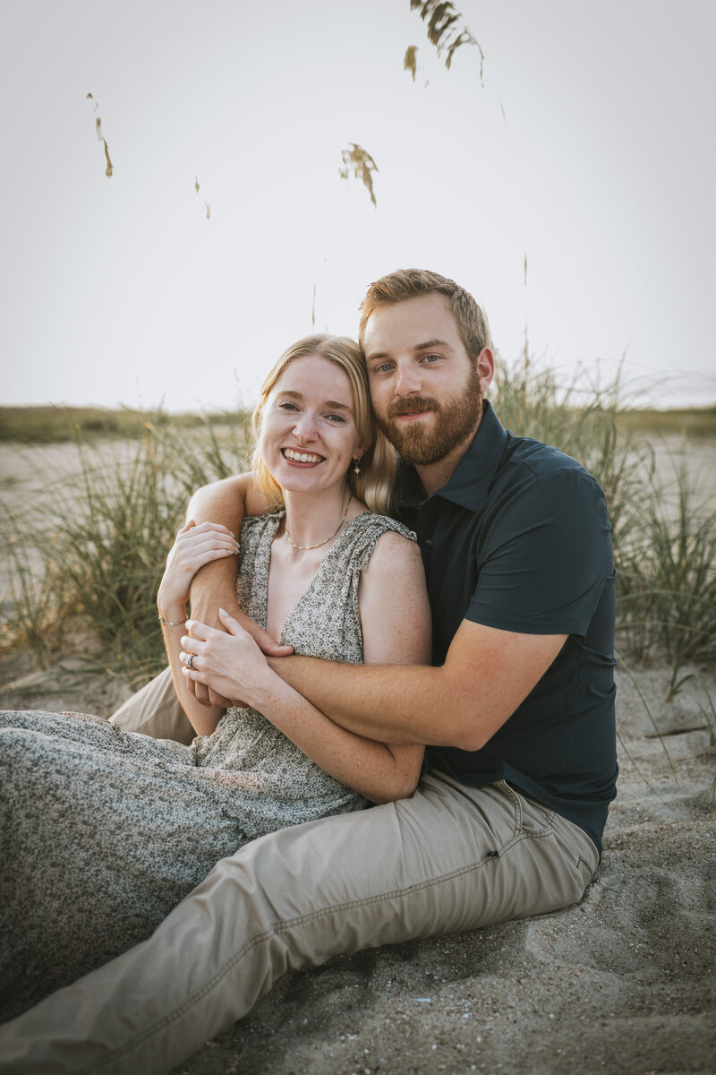 couple sitting on the sand at hilton head engagement session