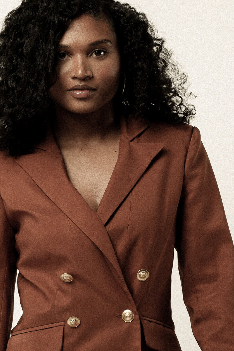 African American woman in a brown blazer with gold buttons