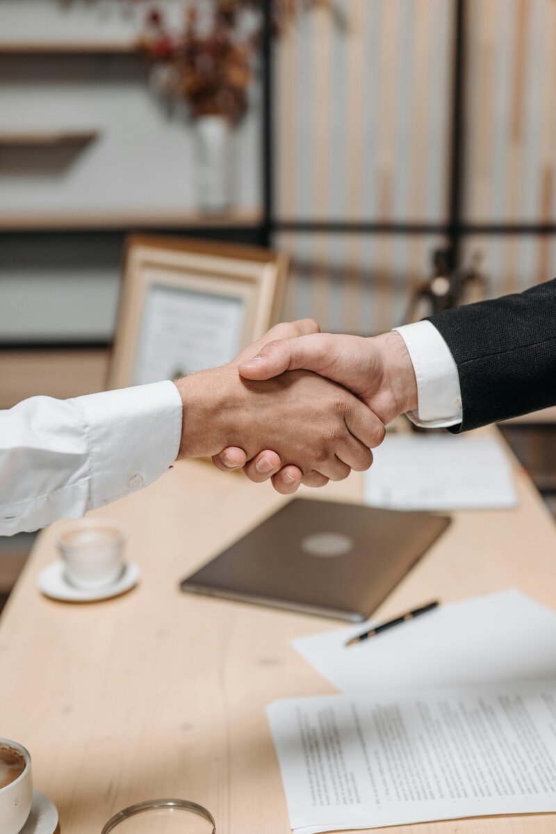 Two businessmen shaking hands over a desk