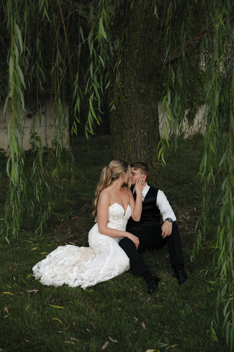Bride and groom share a kiss under Haseltine Estate's willow tree.