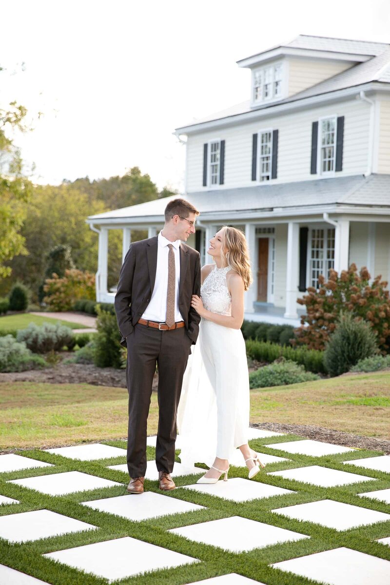 Bride and Groom looking into each other's eyes  in front of Walnut Hill House in Raleigh, NC