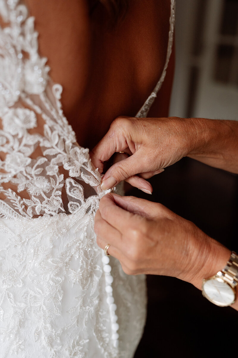 moeder knoopt jurk van bruid