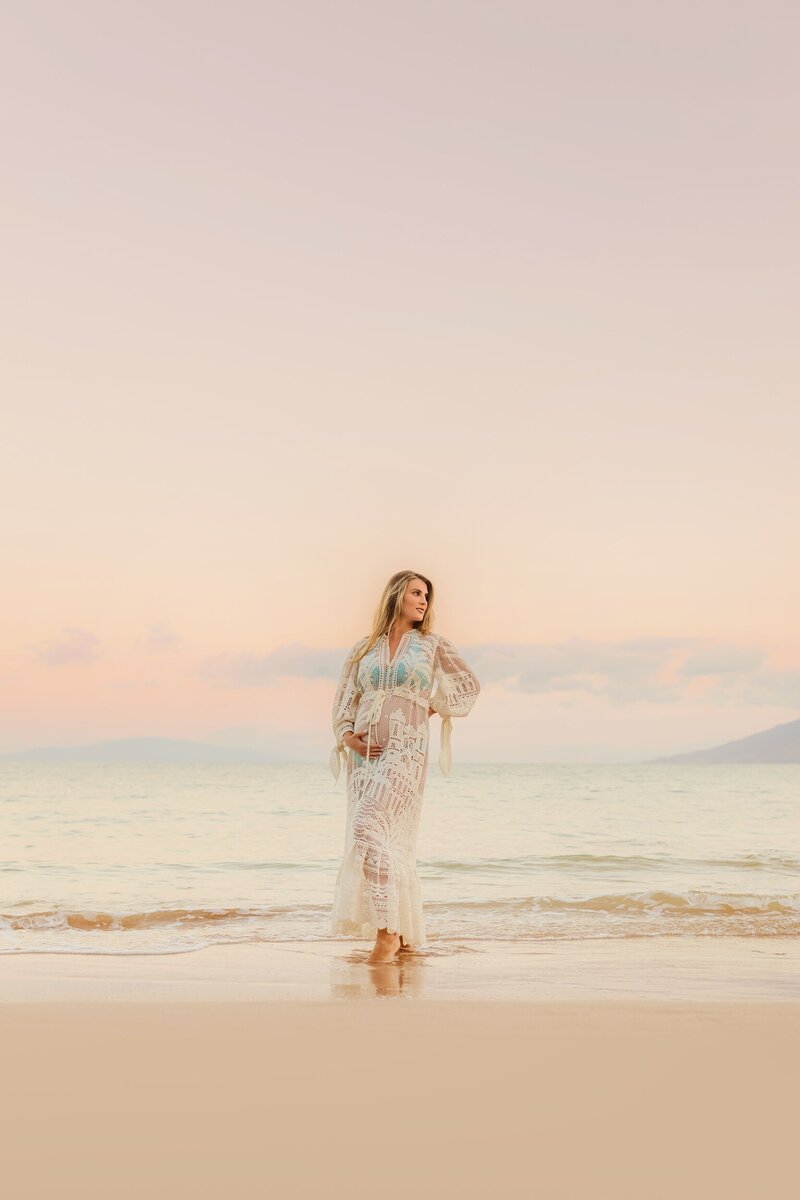 pastel maternity portrait with pregnant woman posing and looking off camera at wailea beach in maui