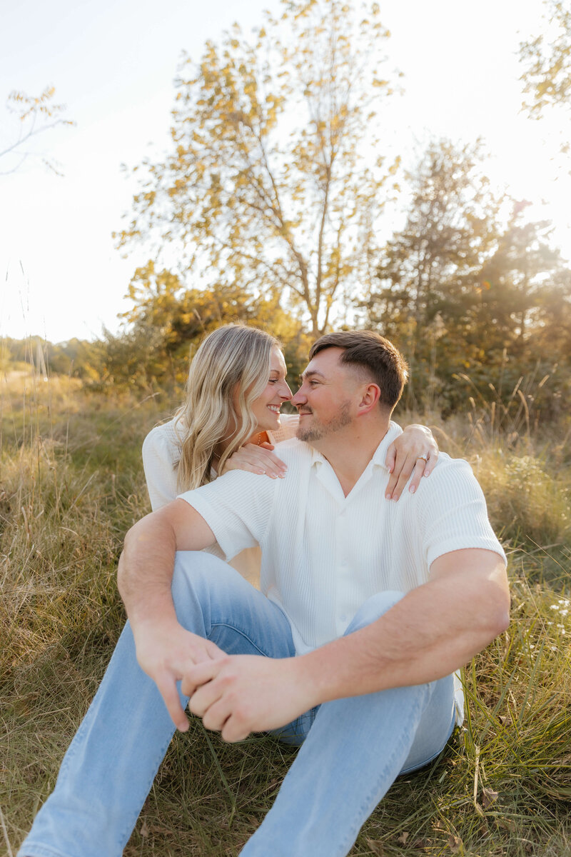 Candid couple smiling in sunlit field, golden hour engagement session for modern Midwest couples who love real, heartfelt moments