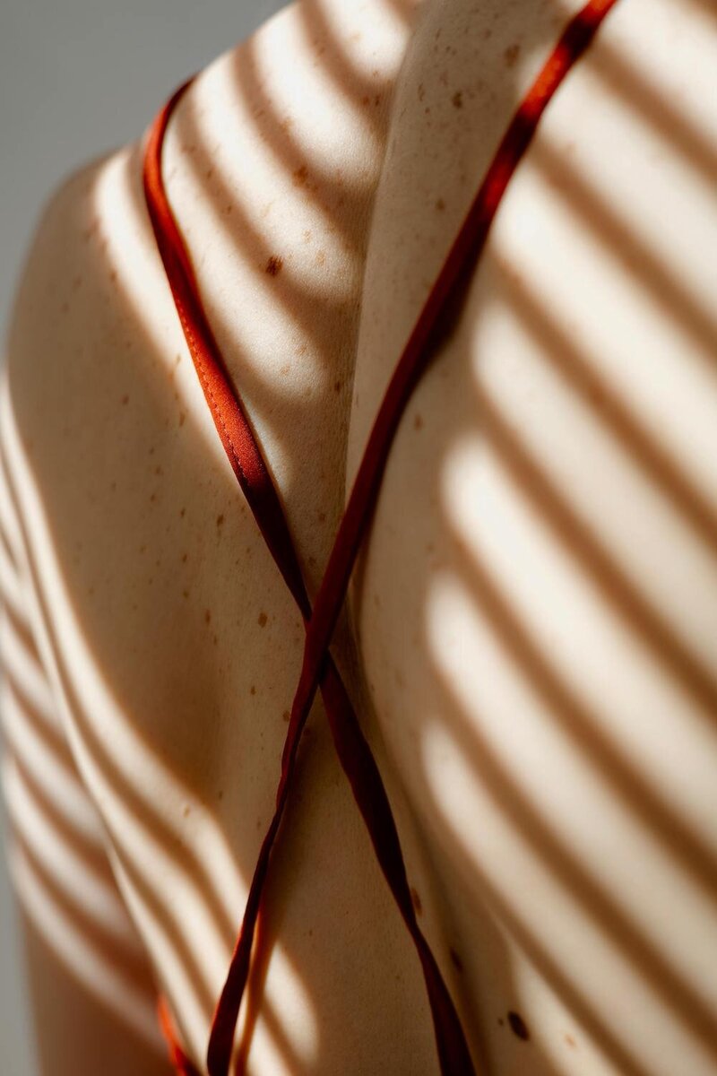 Ayurvedic Skin Specialist, Jen, wearing a white top and pants sitting on a jute rug leaning against a neutral couch