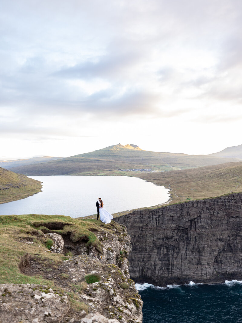 Faroe Islands elopement photography – adventurous couple on cliffs at Gásadalur waterfall.