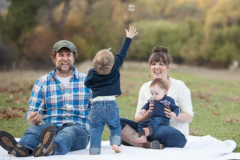 Fun family sitting on blanket chasing bubbles and laughing