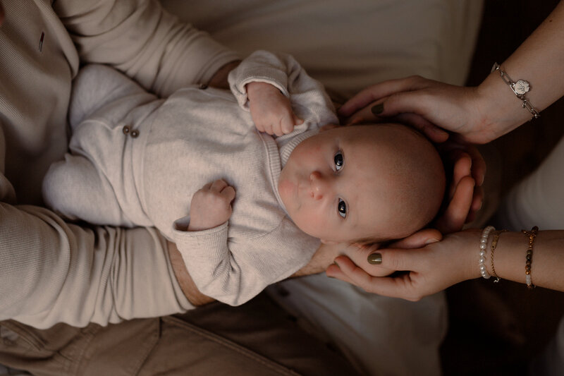 Baby ligt tussen de armen en handen van zijn ouders tijdens een newbornshoot door Joenne Bokhorst fotografie