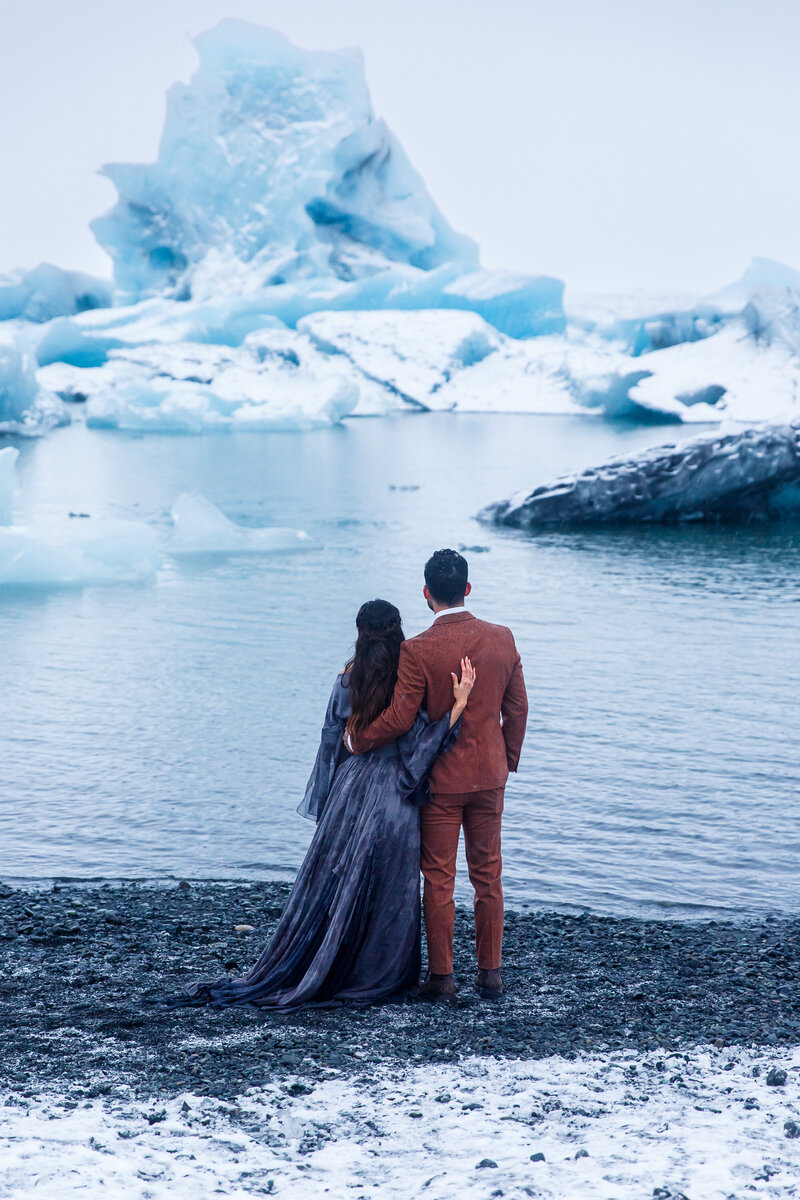 An eloping couple stares out at huge glaciers during their Iceland Glacier Lagoon elopement.