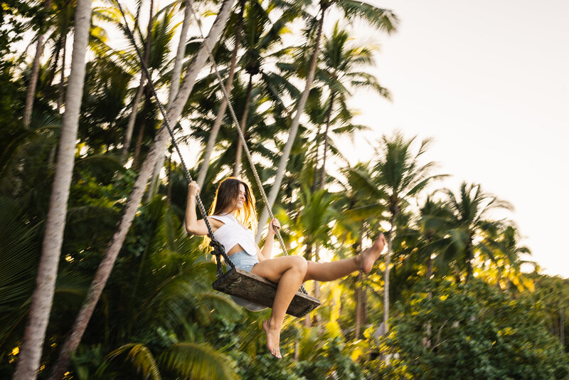 Woman swings on a  seated rope swing in front of a jungle in Panama