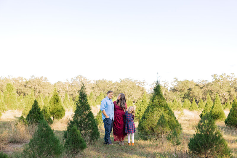 family of 3 at a christmas tree farm.