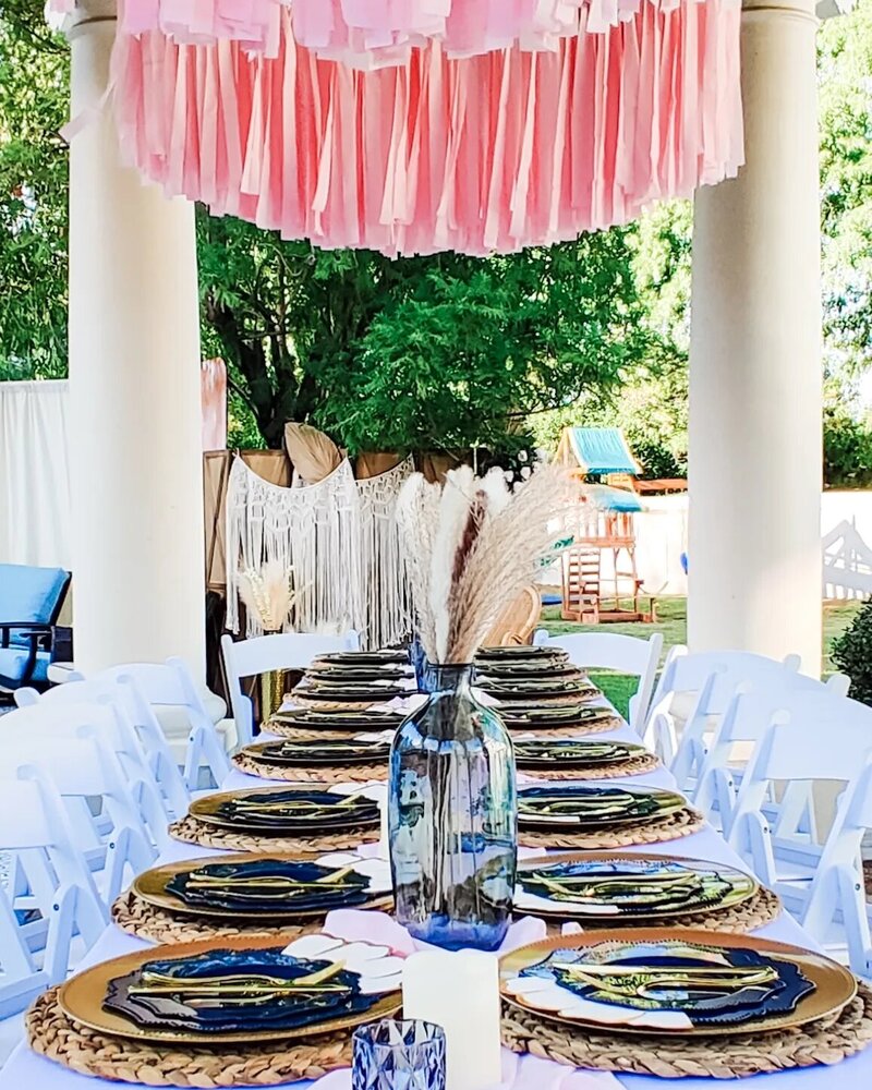 Elegant Arizona event table setup with navy and gold plates, woven chargers, gold flatware, and centerpiece vases styled by Stars and Stripes Events LLC.