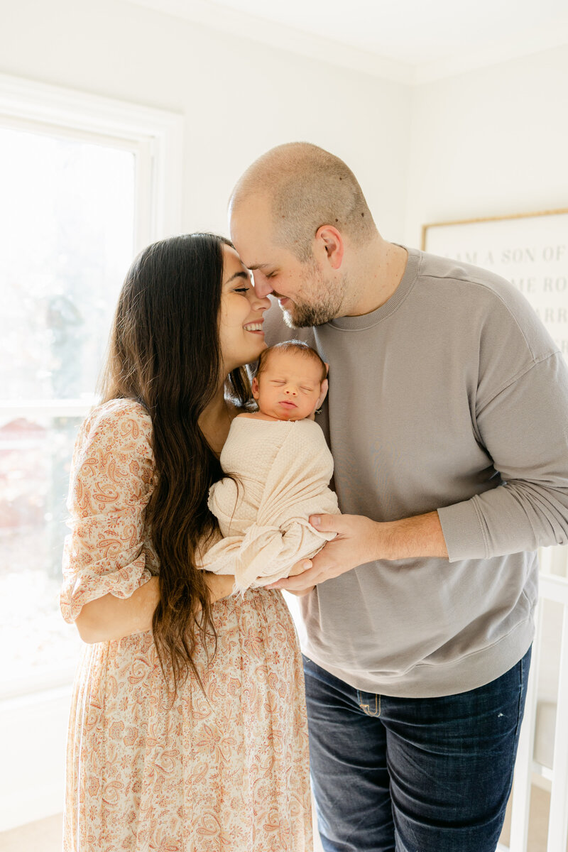 Mother, Father, and newborn baby in neutral clothing newborn session.
