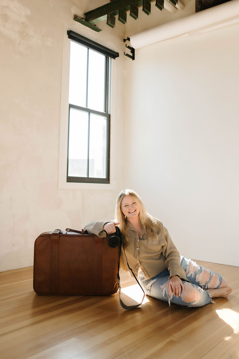 Adventure wedding and elopement photographer leans onto her suitcase, ready to take off on her next adventure elopement adventure. 