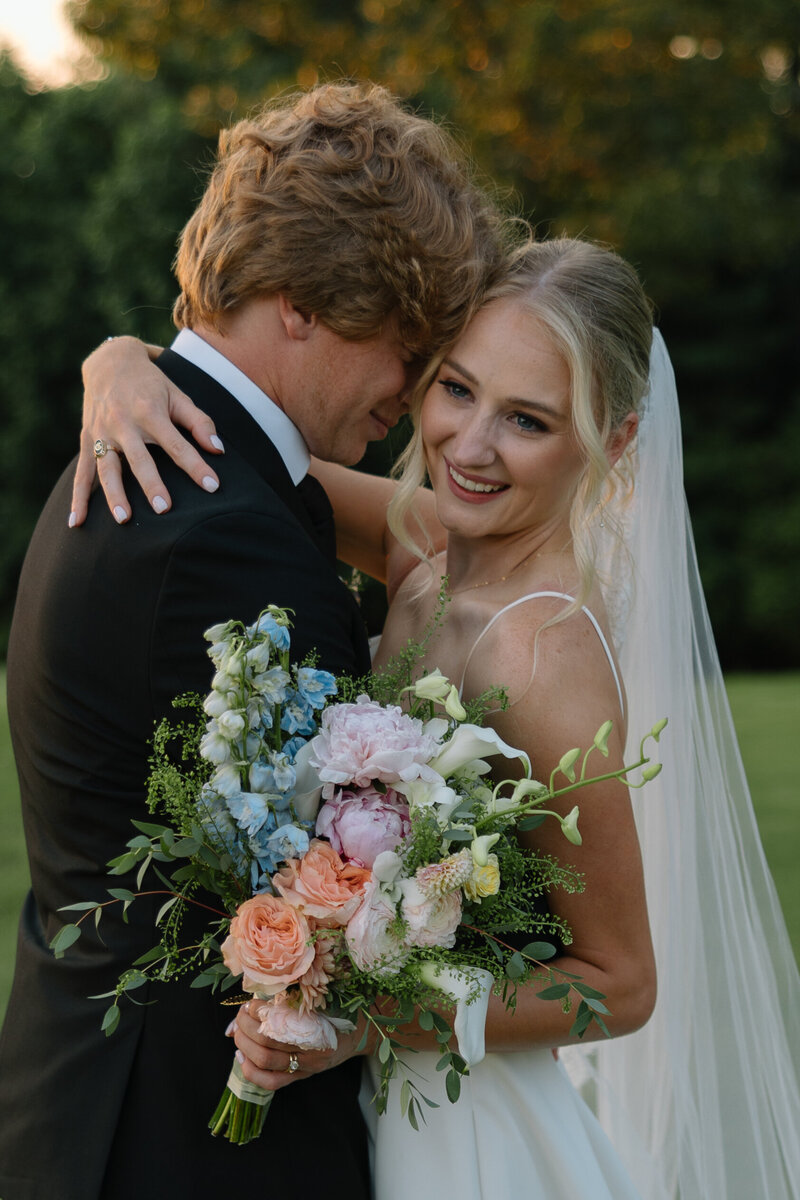 Colorful bridal bouquet full of peonies, roses, lilacs, delphiniums, and greenery.