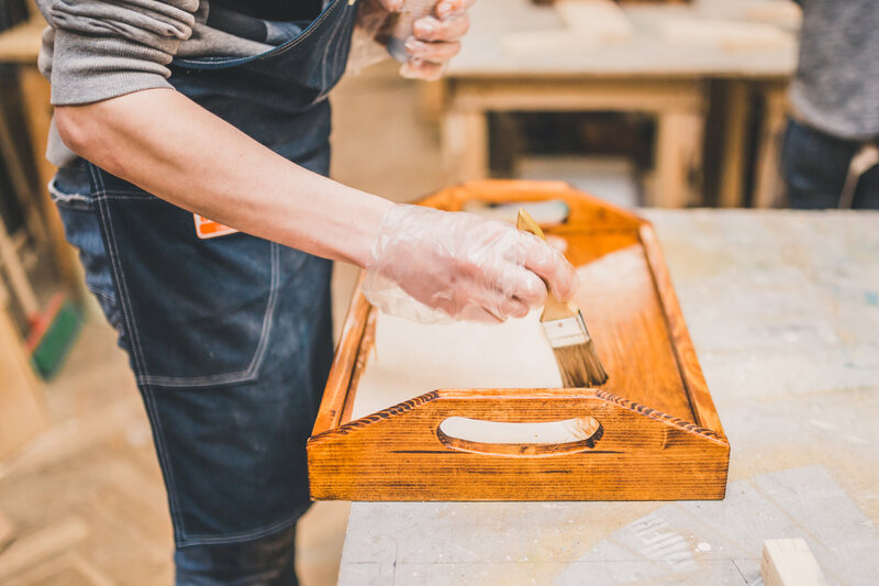 Man painting varnish on a wooden tray