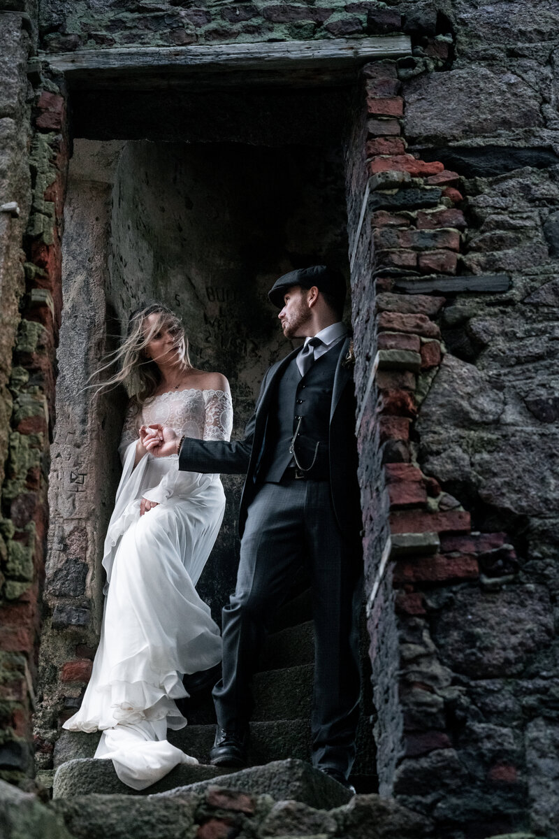Couple walk down the stairs during their scottish elopement at Slains Caslte
