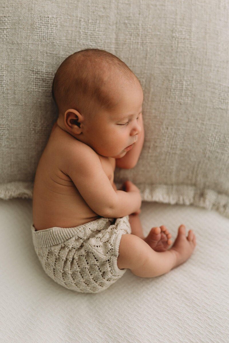 Newborn in studio session with baby sleeping on a pillow in Kelowna B.C wearing neutral clothes