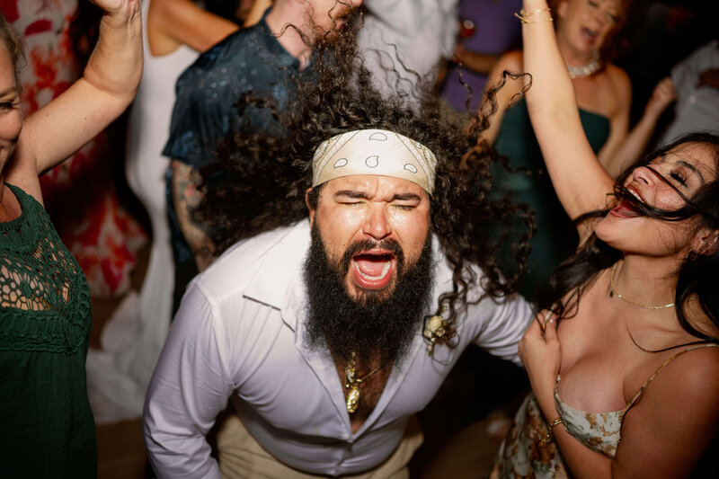 A bearded man dancing at a wedding party.