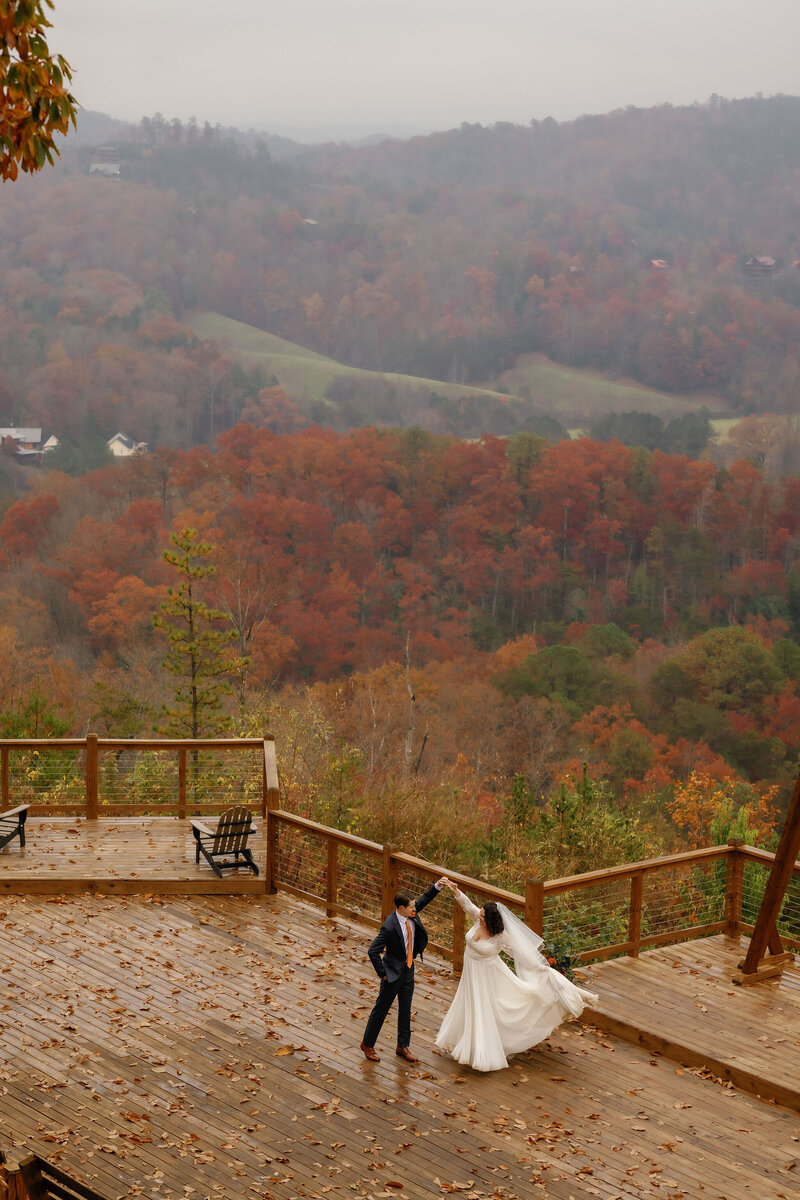 fall elopement in the Smokies mountains with bride and groom dancing together on a deck at a venue in the mountains