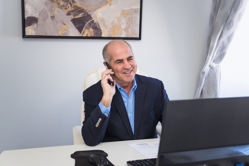The owner of Peak Private Lending smiling and talking on the phone with his client.