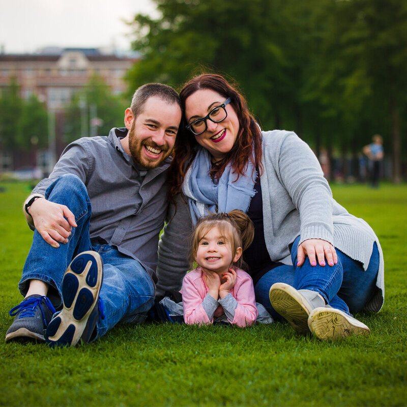 A family sits on the grass in front of a building.