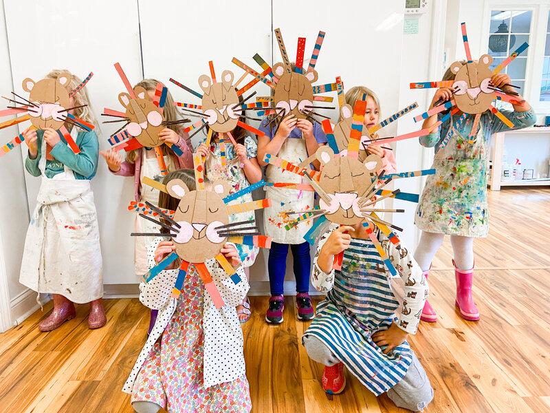Campers holding up lion masks at artcie art studio