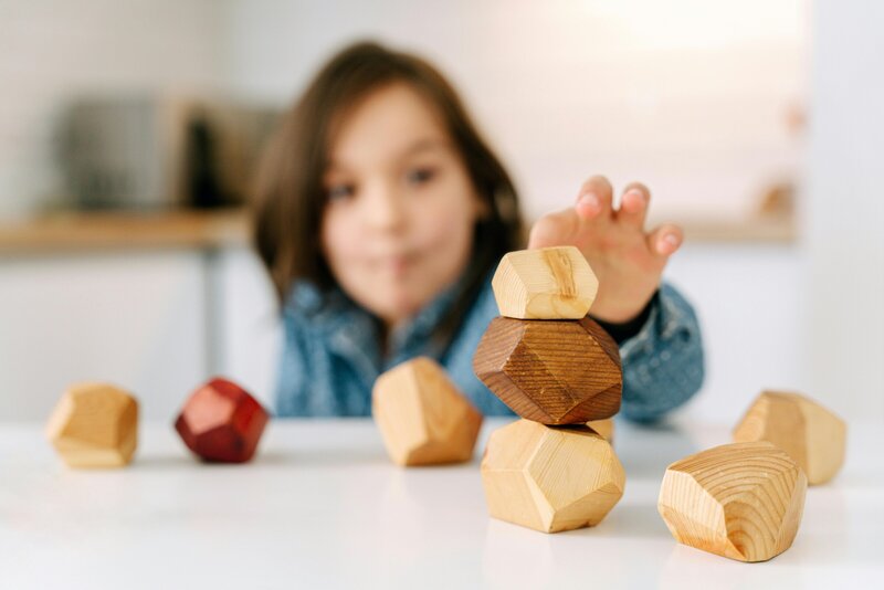 Stacking wooden toys on a table with little boy in the background