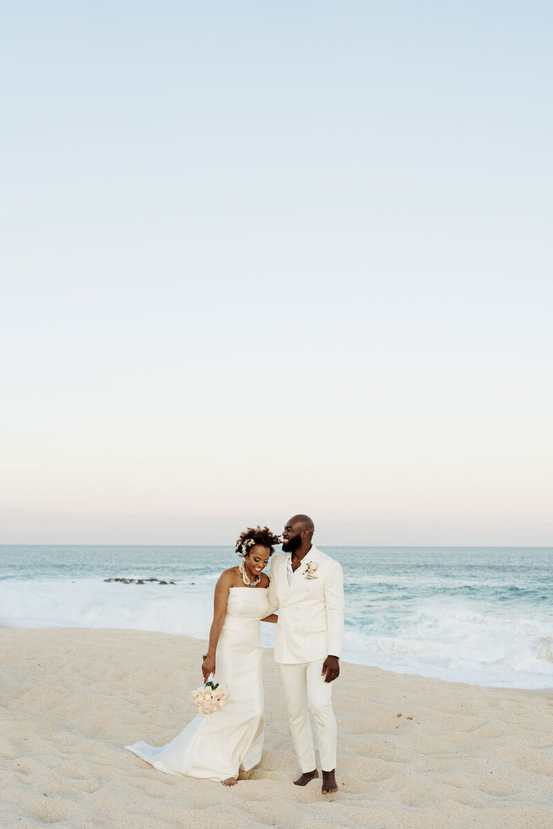 Bride and groom smiling together on a sandy beach