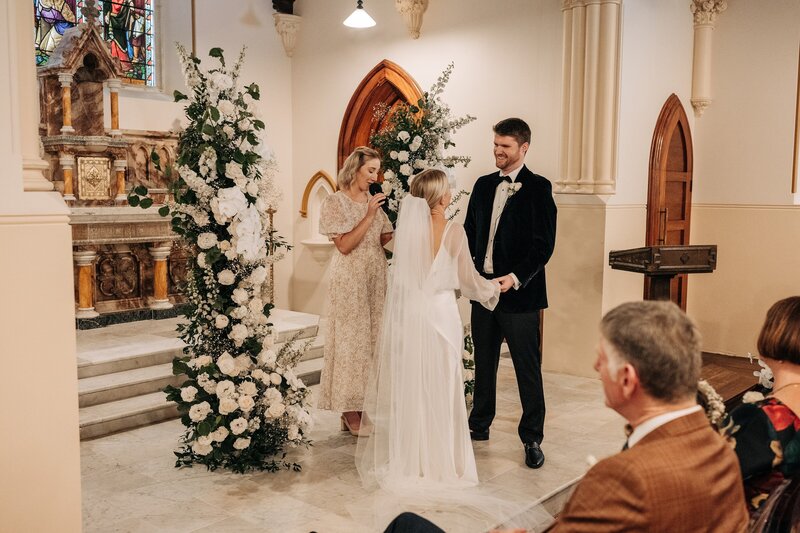 a bride and groom with pillars of white florals by the flower press christchurch