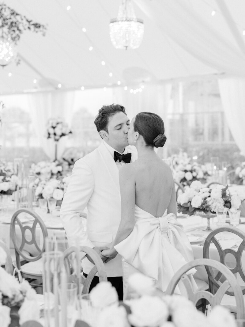 Couple in wedding attire kissing in their reception space
